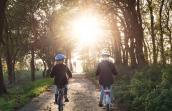 Un enfant et un homme à vélo sur une route de campagne